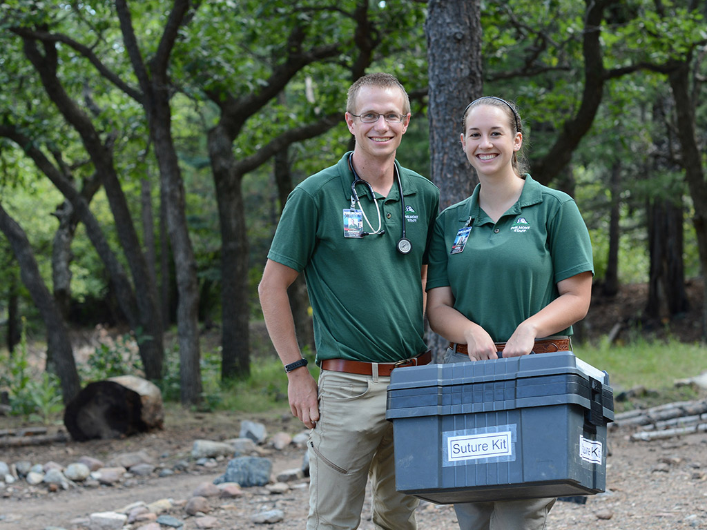 Male and female student posing outside with a Suture kit box in one hand